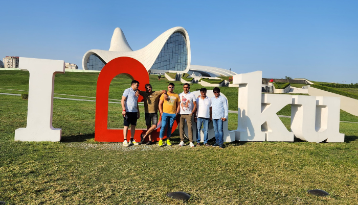 Azerbaijan tour packages: Group of friends posing in front of the "I Love Baku" sign with the modern Heydar Aliyev Center building in the background.